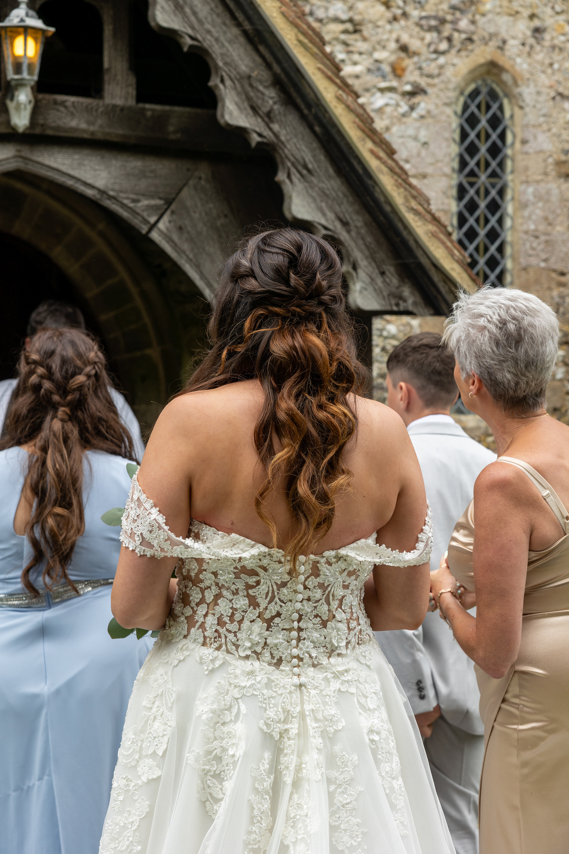 Bride in a lace wedding dress standing outside a historic church moments before the wedding ceremony.