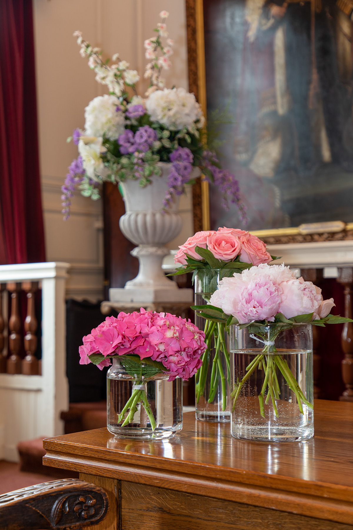 Pink and white wedding flowers displayed in glass vases inside an elegant ceremony room.